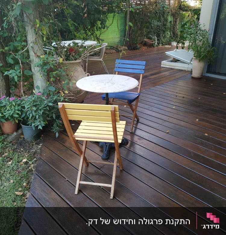 שולחן עגול עם כיסאות צבעוניים על דק עץ בגינה